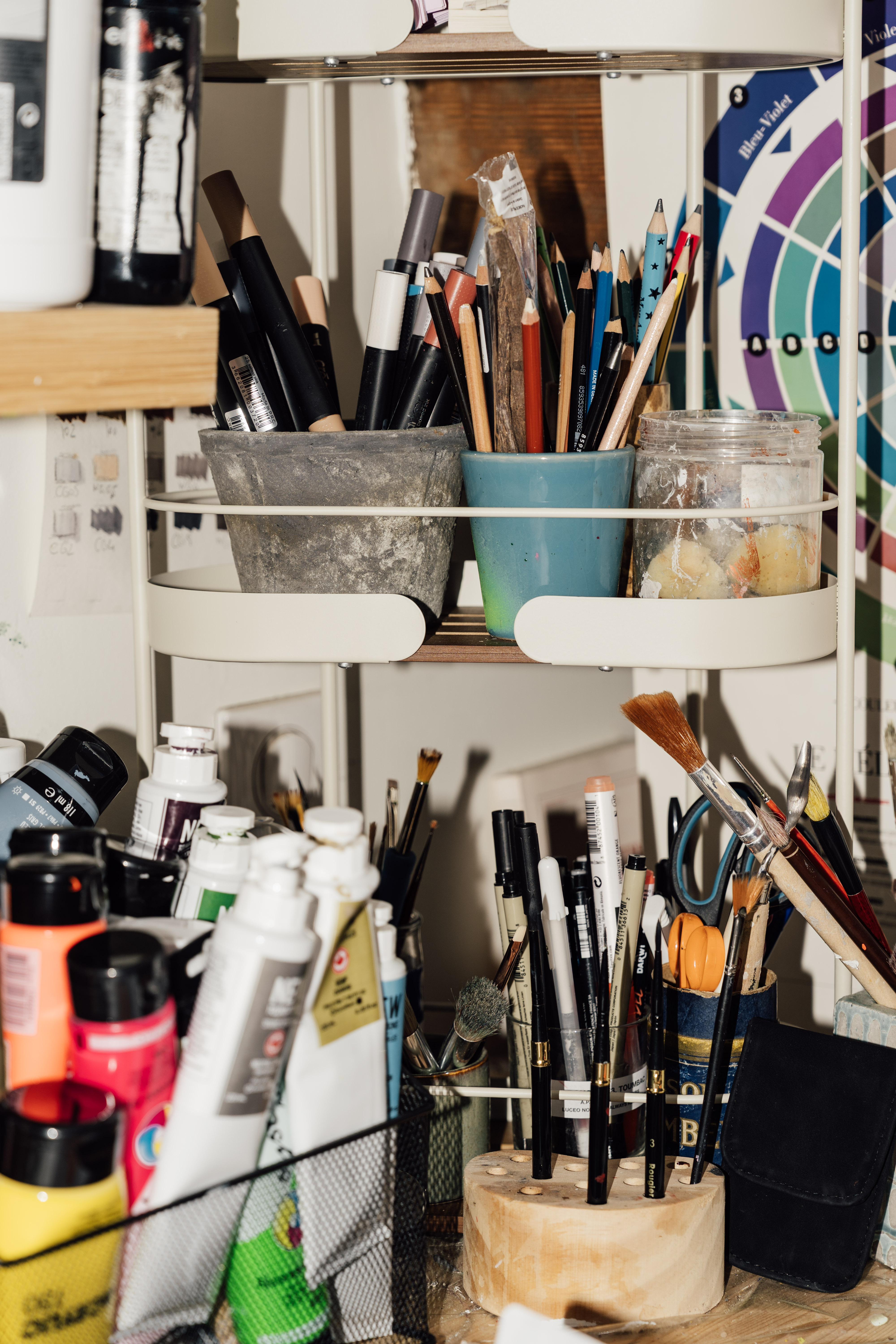 Pinceaux, tubes de peinture et crayons rangés sur une étagère