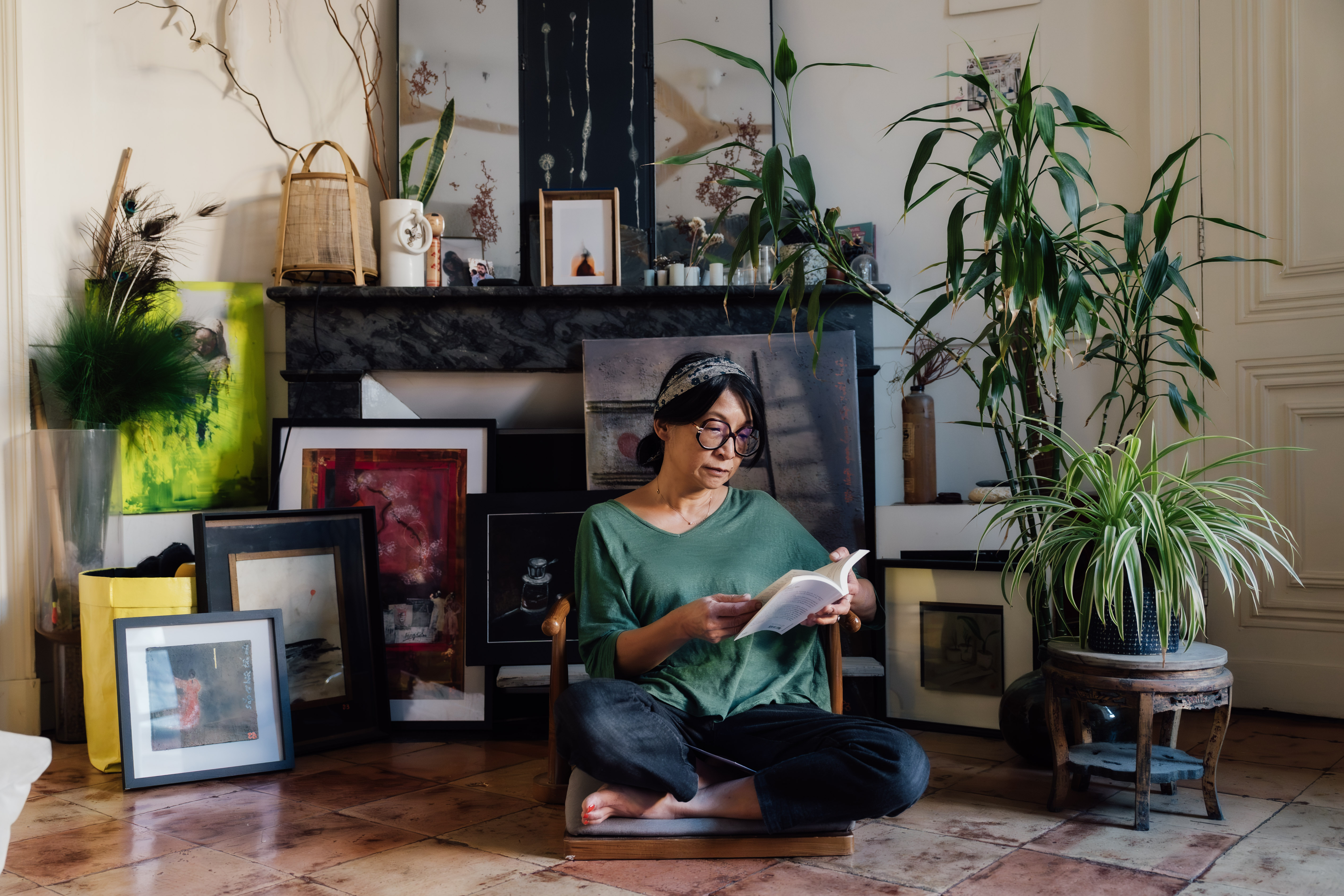 Bao en pleine lecture, entourée de ses tableaux et de ses plantes